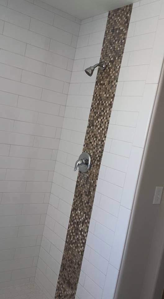 Finished white subway tile shower with a vertical pebble mosaic accent stripe
